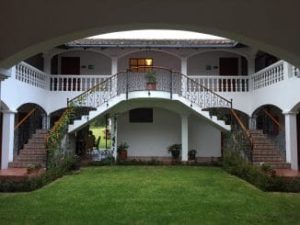 Courtyard of hotel--green lawn surrounded by white building with second floor balconies and center staircase