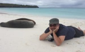 Man in hat and sunglasses lying on a beach in Espanola, holding his chin in his hands